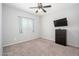 Carpeted bedroom with a ceiling fan, a window, and a dresser with television at 25951 W Piute Ave, Buckeye, AZ 85396