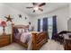Cozy bedroom with wooden bed frame, ceiling fan, and window offering natural light and neighborhood views at 30388 N Opal Dr, San Tan Valley, AZ 85143