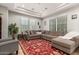 Spacious living room featuring a large sectional sofa, tray ceiling, and natural light from big windows at 3331 N Acacia Way, Buckeye, AZ 85396