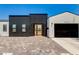 Striking contemporary home with unique black corrugated facade, a wooden door, and brick driveway at 4246 E Mulberry Dr, Phoenix, AZ 85018