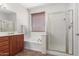 The bright bathroom features a large window, a tub, and a glass enclosed shower at 7008 W Southgate Ave, Phoenix, AZ 85043