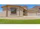 Tan home with two-car garage, desert landscaping, and small patch of grass at 7008 W Southgate Ave, Phoenix, AZ 85043