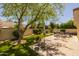 Landscaped backyard featuring seating, a mature shade tree, and artificial turf at 10429 N 101St St, Scottsdale, AZ 85258