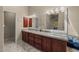 A bathroom vanity with wood cabinets, granite countertop and double sinks with a view into the house at 10429 N 101St St, Scottsdale, AZ 85258