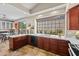 Bright kitchen boasts dark wood cabinets, white countertops, stainless steel appliances, travertine floors, and large window at 10429 N 101St St, Scottsdale, AZ 85258