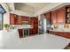 Spacious kitchen with dark wood cabinetry, white countertops, stainless steel appliances, and travertine tile flooring at 10429 N 101St St, Scottsdale, AZ 85258