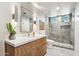 Bright bathroom featuring dual sinks, stylish vanity, walk-in shower, and modern lighting at 10651 E Fernwood Ln, Scottsdale, AZ 85262