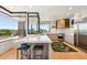 Bright and spacious kitchen featuring large windows, stainless appliances, island seating, and tile backsplash at 10651 E Fernwood Ln, Scottsdale, AZ 85262