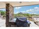 Cozy outdoor kitchen with stone accents and a view of the pool at 10651 E Fernwood Ln, Scottsdale, AZ 85262