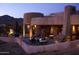 Inviting outdoor patio with tables, chairs, and beautiful stone architecture at twilight at 10651 E Fernwood Ln, Scottsdale, AZ 85262