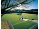 A tree framed view features tennis players in the community's beautifully maintained tennis court under a clear sky at 10651 E Fernwood Ln, Scottsdale, AZ 85262
