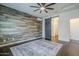 Spacious bedroom with a wood-look accent wall, ceiling fan, and ensuite bathroom access at 10925 E Toluca Ave, Mesa, AZ 85212