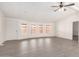 Spacious living room with gray floors, three large windows, and a ceiling fan at 11000 N 91St Ave # 20, Peoria, AZ 85345