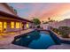 A backyard pool featuring a tanning ledge reflects the setting sun as the home's windows glow warmly at 11085 E Mary Katherine Dr, Scottsdale, AZ 85259