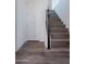 Hardwood stairs with a dark wood railing next to a white door and white walls at 11300 N Casa Dega Dr # 1005, Surprise, AZ 85388