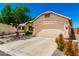 Beige single-story home with a two-car garage, desert landscaping, and a concrete driveway at 11669 W Pine Mountain Ct, Surprise, AZ 85378