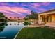 Waterfront backyard showcasing a serene pond view, complemented by lush landscaping and a covered patio at 1724 W Blue Ridge Way, Chandler, AZ 85248