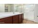 Bathroom with wood floors, shower, and stylish vanity with a white countertop and brown wood cabinets at 18514 W Williams Rd, Surprise, AZ 85387