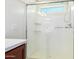 Bright bathroom featuring glass shower with small window, wall-mounted shower head, and convenient shelving at 18514 W Williams Rd, Surprise, AZ 85387