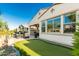 Low-maintenance backyard featuring a putting green, covered patio, and lush desert landscaping at 20784 W Minnezona Ave, Buckeye, AZ 85396