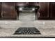 Close up shot of a gas cooktop with tiled backsplash and stainless vent at 20784 W Minnezona Ave, Buckeye, AZ 85396