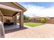 Large backyard with a covered patio, artificial turf, and well-maintained landscaping at 2562 N Springfield St, Buckeye, AZ 85396