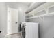 Well-organized laundry room features floating shelves, tile flooring, and a white door at 2562 N Springfield St, Buckeye, AZ 85396