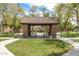 A shaded picnic pavilion with red tile roof sits near a grassy lawn and walking path, lined by trees at 2562 N Springfield St, Buckeye, AZ 85396