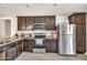 Well-lit kitchen featuring dark wood cabinets, granite countertops, and stainless steel appliances at 25787 W Allen St, Buckeye, AZ 85326