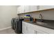 Well-equipped laundry room featuring modern washer and dryer, sink and sleek cabinets at 27647 N 176Th Dr, Surprise, AZ 85387