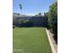Spacious backyard with artificial turf, a wooden fence, mature trees, and lush foliage at 3512 S Elm St, Tempe, AZ 85282