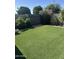View of the green backyard with artificial turf, a wooden fence, and lush foliage at 3512 S Elm St, Tempe, AZ 85282
