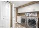 Functional laundry room with a modern washer and dryer set, storage cabinets, and a tiled floor at 3512 S Elm St, Tempe, AZ 85282
