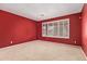Bedroom with red accent wall, neutral carpet, and plantation shutters at 5919 W Straight Arrow Ln, Phoenix, AZ 85083