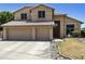 Inviting two-story home boasts a three-car garage, desert landscaping, and a neutral stucco facade under a sunny sky at 5957 W Robin Ln, Glendale, AZ 85310
