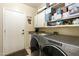 Functional laundry room with modern washer and dryer, ample storage cabinets and convenient sink at 5957 W Robin Ln, Glendale, AZ 85310