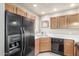 Bright kitchen showcasing a black refrigerator, wooden cabinets, stainless sink, and black dishwasher at 7101 W Beardsley Rd # 542, Glendale, AZ 85308