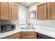 Corner of kitchen showing a stainless sink with wooden cabinets, black dishwasher, and a microwave at 7101 W Beardsley Rd # 542, Glendale, AZ 85308