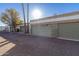 View of well-maintained garages with neutral paint and mature trees under a blue sky at 7132 N 63Rd Dr, Glendale, AZ 85301