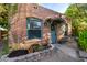 Quaint home features a brick exterior with arched window and a charming blue front door and landscaping at 725 W Portland St, Phoenix, AZ 85007