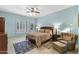 Bedroom with blue walls features a wooden bed frame, ceiling fan, and window with white shutters at 7335 E Quail Track Rd, Scottsdale, AZ 85266