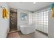 Bright bathroom featuring a standalone tub, a glass-block window, and a large tiled shower at 7533 N 8Th St, Phoenix, AZ 85020