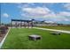 Inviting community area with a playground, cornhole, picnic tables, and shade structures on artificial turf at 7836 E Quintana Ave, Mesa, AZ 85212