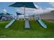 Community playground featuring slides, artificial grass, and shade structures for enjoyment at 7836 E Quintana Ave, Mesa, AZ 85212