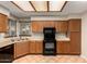 Well-lit kitchen with tile floors, wood cabinets, and modern black appliances at 9002 W Caribbean Ln, Peoria, AZ 85381