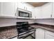 This well-equipped kitchen boasts granite counters and a black electric stove and microwave at 11375 E Sahuaro Dr # 1053, Scottsdale, AZ 85259