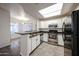 This bright kitchen features white cabinets, black appliances, granite counter and an open breakfast bar at 11375 E Sahuaro Dr # 1053, Scottsdale, AZ 85259