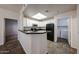 Well-lit kitchen features white cabinetry, black appliances, breakfast bar, and convenient laundry access at 11375 E Sahuaro Dr # 1053, Scottsdale, AZ 85259