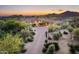 Expansive aerial view of estate with a circular driveway, lush desert landscaping, and mountain views at sunset at 11548 E Salero Dr, Scottsdale, AZ 85262