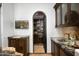 Elegant bar featuring custom cabinetry, marble countertops, and an arched entryway to a wine storage area at 11548 E Salero Dr, Scottsdale, AZ 85262